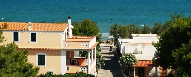 Case vicino al mare, alberi verdi e cielo blu.