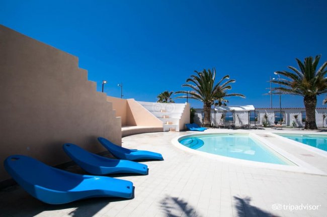 Piscina con lettini blu e palme.