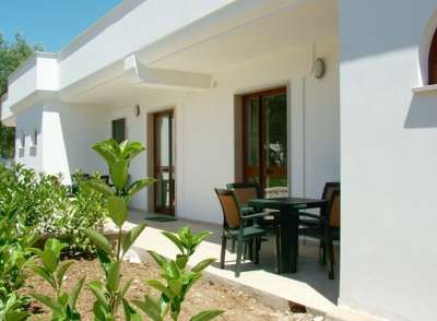 Veranda con tavolo e sedie, affaccio su giardino curato.