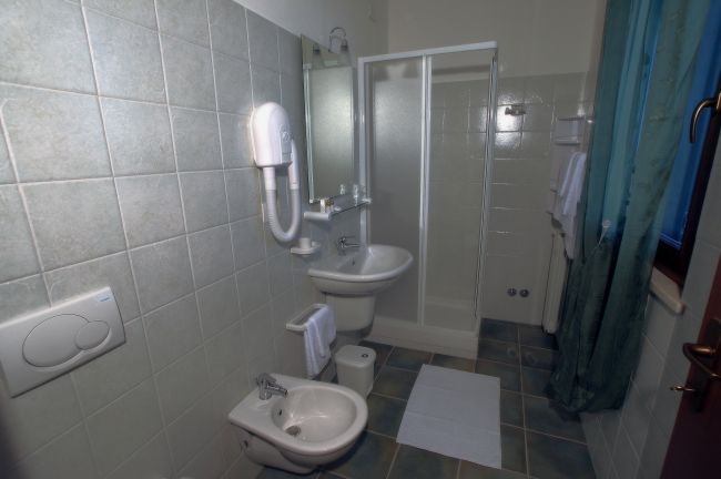 Bagno con doccia, lavandino, bidet e asciugacapelli sul muro.