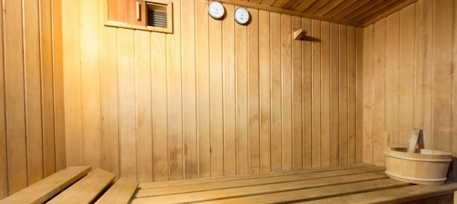 Interno di sauna in legno con panche e strumenti.