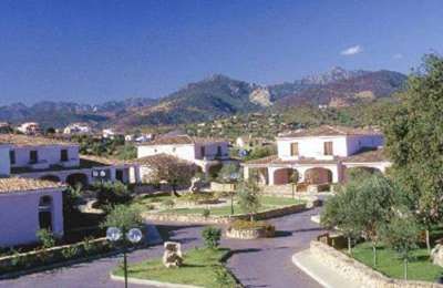 Complesso residenziale con case bianche e montagne sullo sfondo.