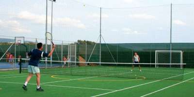 Due persone giocano a tennis su un campo all'aperto.