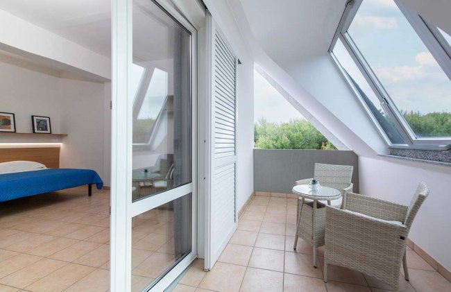 Camera con terrazza e poltroncine bianche.