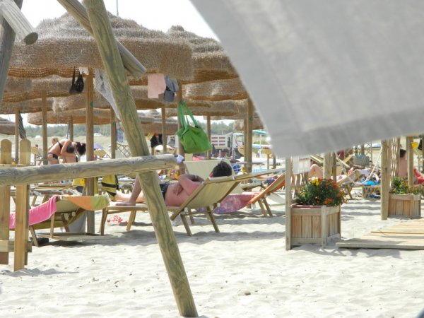 Persone rilassate sotto ombrelloni sulla spiaggia.