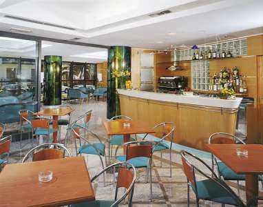 Sala bar arredata con tavoli e sedie, bancone e bottiglie esposte.