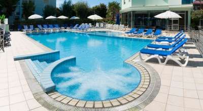 Ampia piscina all'aperto con area idromassaggio circolare e lettini blu.