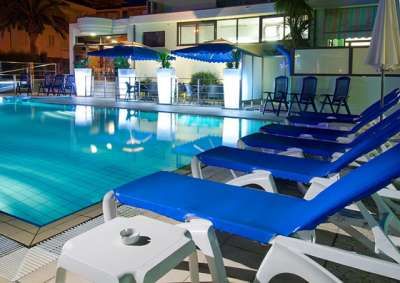 Sedie a sdraio blu intorno a una piscina illuminata di notte.