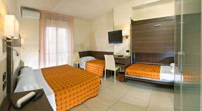 Camera d'albergo con letto matrimoniale e letto singolo a scomparsa, copriletti arancioni.