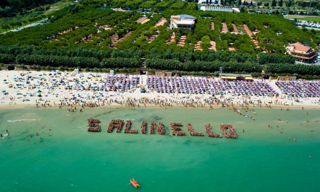 Spiaggia affollata con persone che formano la scritta 