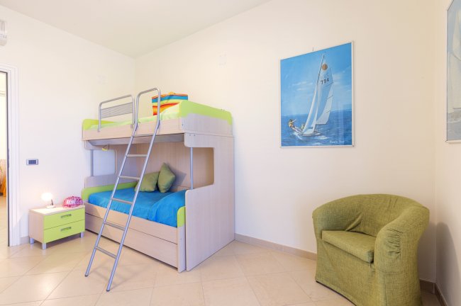 Camera con letti a castello, sedia e quadro.