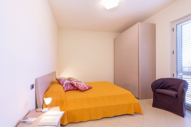 Camera con letto matrimoniale e poltrona.