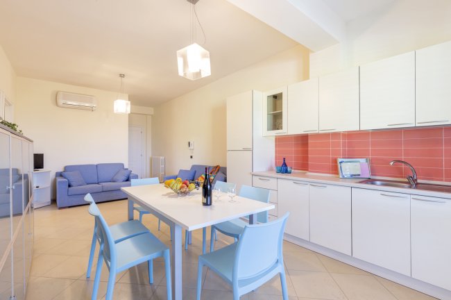 Cucina e sala con tavolo bianco e sedie blu.