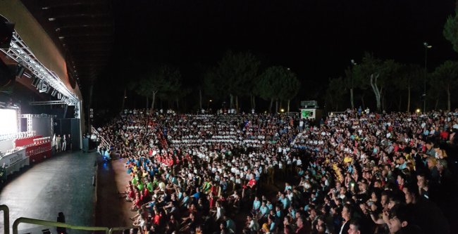 Grande folla in un anfiteatro all'aperto di notte.