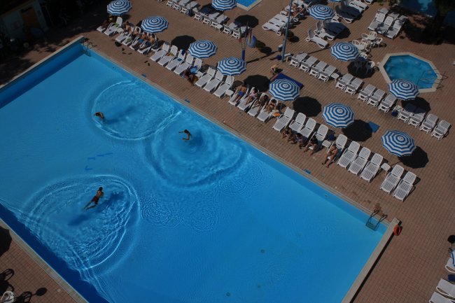 Piscina con ombrelloni a righe bianche e blu.