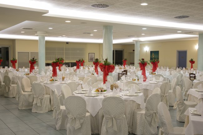 Sala banchetti con tavoli e sedie bianche.
