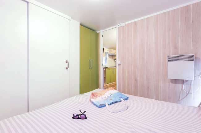 Camera con letto, occhiali da sole e borsa colorata.