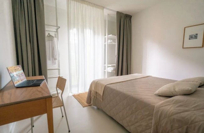 Camera da letto con scrivania, letto e armadio a vista.
