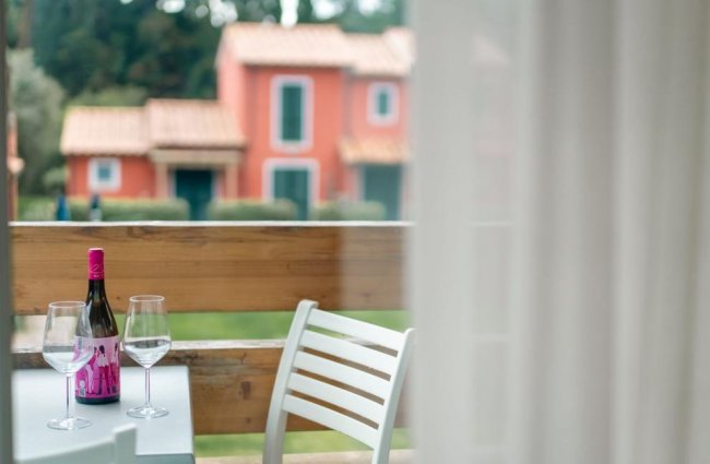 Tavolo all'aperto con vino e due bicchieri.