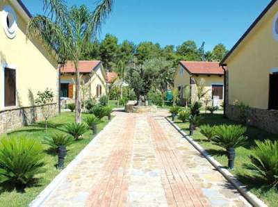 Vialetto di pietra con palazzi gialli e giardino curato.