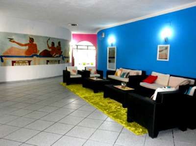 Sala d'attesa con divani neri, pareti blu e un dipinto grande.