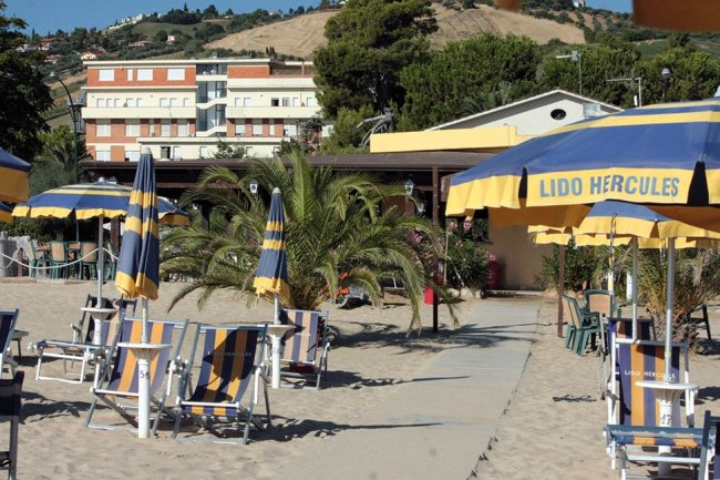 Spiaggia con ombrelloni e edifici sullo sfondo.