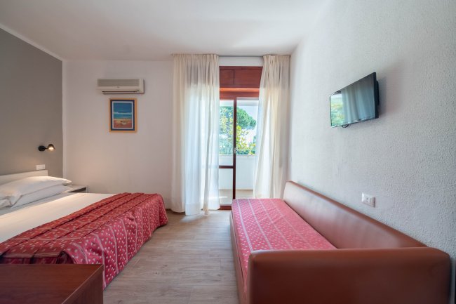 Camera con letto matrimoniale e divano rosso.