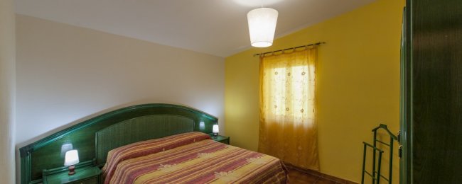 Camera con letto matrimoniale e parete gialla.