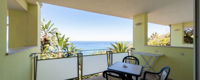 Balcone con tavolo e sedie, vista mare.
