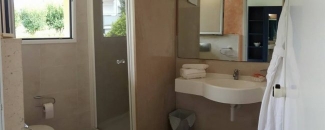 Bagno con doccia, lavandino e specchio.