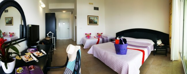 Camera d'hotel con tre letti e arredi moderni.