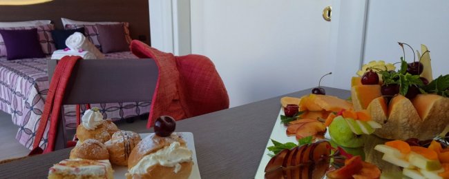 Dolci e frutta su un tavolo, camera sullo sfondo.