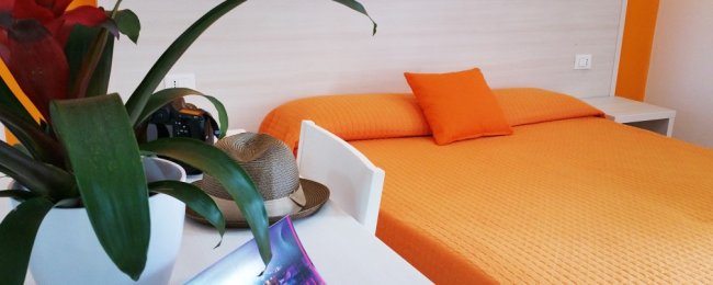 Letto arancione con pianta e cappello su un tavolo.