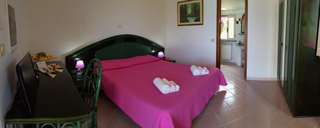 Letto matrimoniale rosa con asciugamani piegati.