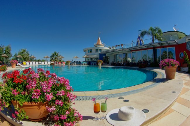 Piscina con fiori, bibite e cappello in primo piano.