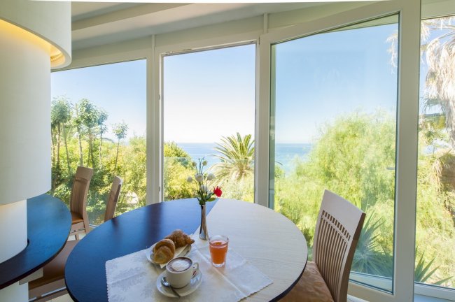 Tavolo con colazione e vista sul giardino e mare.