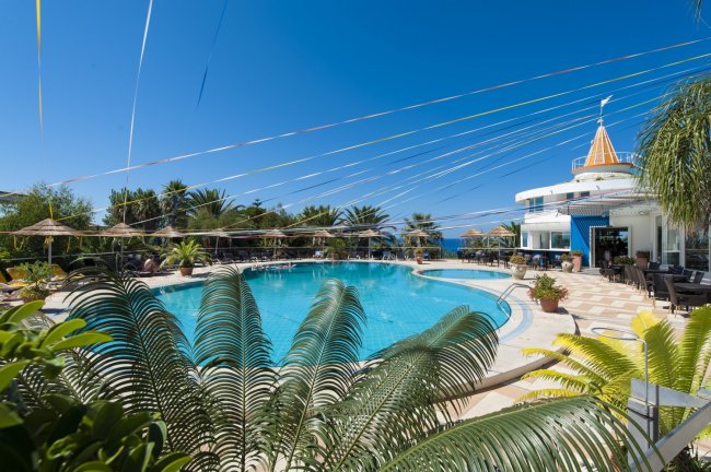 Piscina con palme, sedie a sdraio e costruzione a forma di cono.