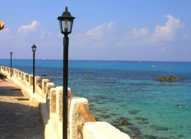Passeggiata sul lungomare con lampioni e mare azzurro.