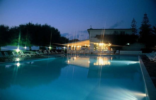 Una piscina illuminata di notte con luci riflesse sull'acqua.