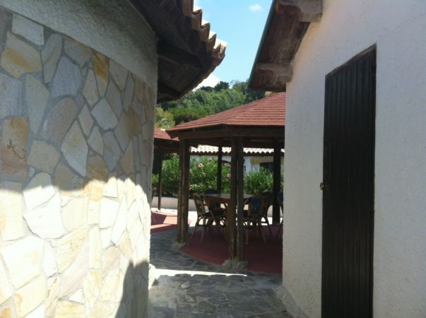 Un patio con tavolino sotto un gazebo in legno.