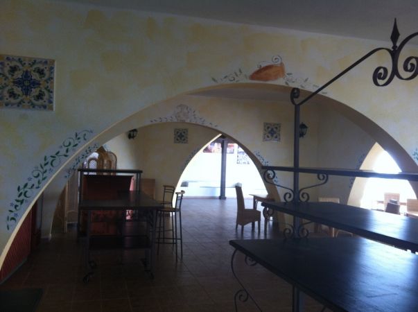 Interno con archi decorati e sedie di legno.
