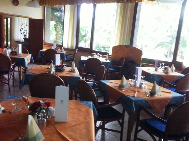 Ristorante con tavoli apparecchiati e finestre.
