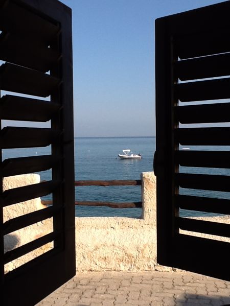 Barca in mare vista tra persiane aperte.