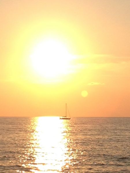 Tramonto sul mare con una barca a vela.