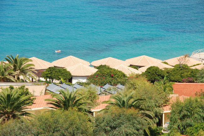 Tetti di bungalow tra palme vicino al mare.