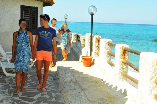 Coppia passeggia lungo una terrazza vista mare.