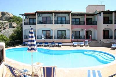 Una piscina con lettini blu e un edificio a due piani sullo sfondo.