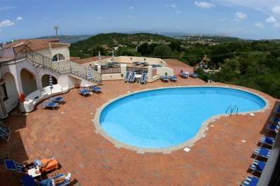 Piscina circondata da lettini su terrazza con vista panoramica.