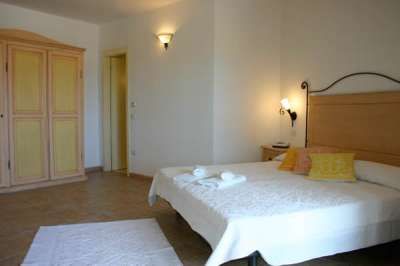 Una camera da letto con letto matrimoniale e armadio, pareti bianche e luci calde.