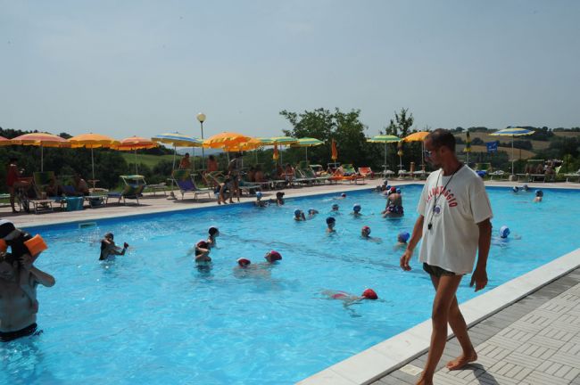 Piscina affollata, bagnino cammina sul bordo.